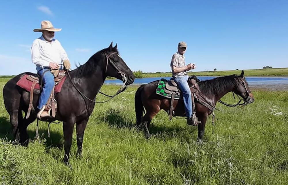 Seth Lauer (on the left) with a friend as they ride pastures,